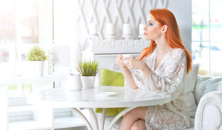 Young beautiful woman holding white cup at homeの写真素材