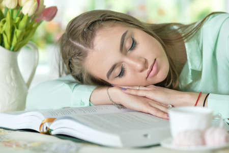 Portrait of young attractive woman sleeping on book