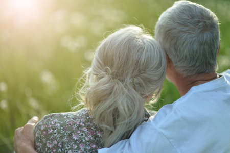 Happy senior coupleon green meadow with dandelionsの写真素材