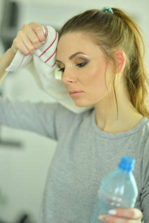 Sporty young woman with water after training in gymの写真素材