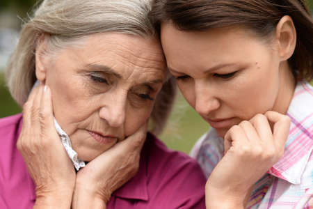 Close up portrait of sad senior woman with adult daughter