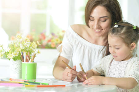 Cute girl with mother drawing at the table