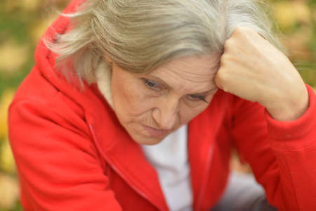 Portrait of sad, thoughtful senior woman in park