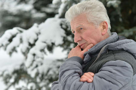 Portrait of senior man standing outdoors in winterの写真素材