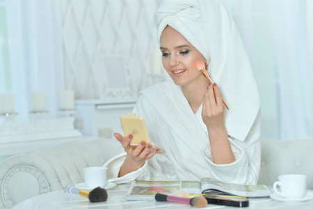 Portrait of young woman applying makeup after showerの写真素材