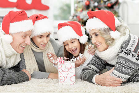 Happy family in Santa hats on the floor with gift