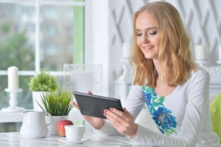 Young beautiful woman with tablet sitting at table