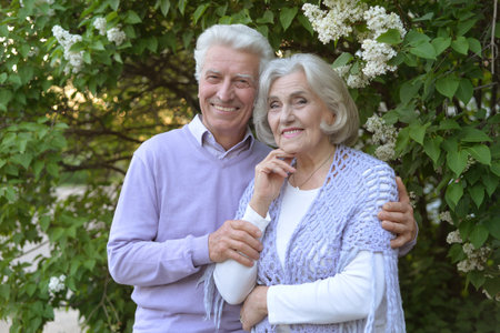 Beautiful senior couple by lilacs in the parkの写真素材