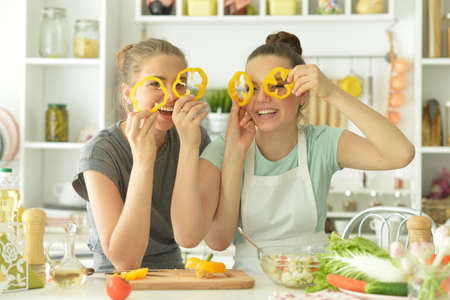Portrait of beautiful teenagers cooking in kitchenの写真素材