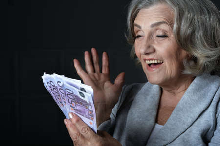 Portrait of happy elderly woman with euros