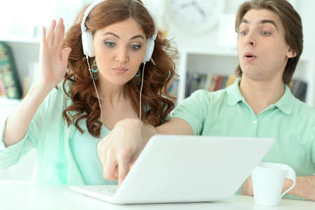 Funny young couple using laptop at home