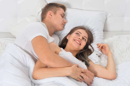Beautiful young couple on soft bed in morning