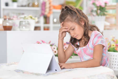 Sad beautiful little girl with tablet pcの写真素材