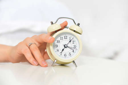 Close up of alarm clock on soft bed on morningの写真素材