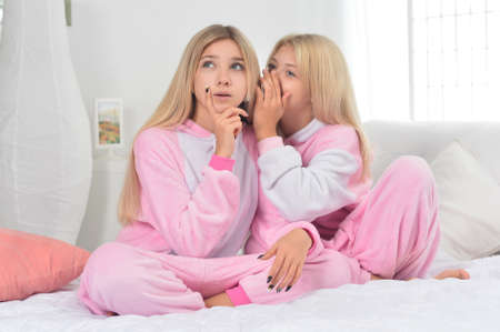 Portrait of girls sharing secret on bedの写真素材