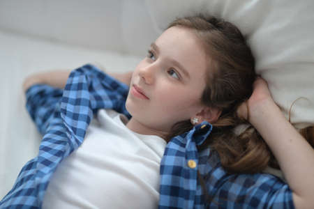 Cute little girl lying in bed at homeの写真素材