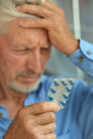 Portrait of sad sick senior man with pillsの写真素材