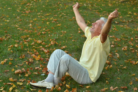 Happy senior man in park sitting on the grassの写真素材