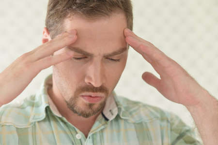 Portrait of handsome young man with headache in studio