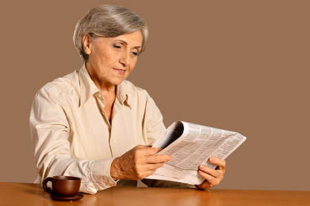 Close up portrait of senior woman reading newspaper