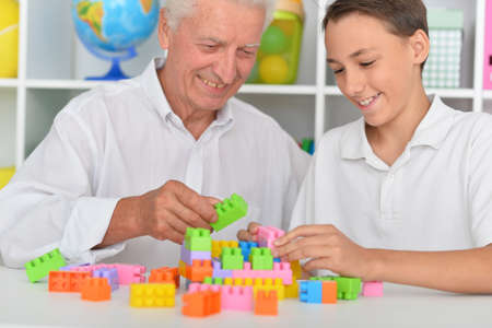 Smiling boy playing with colorful plastic blocks with grandfather