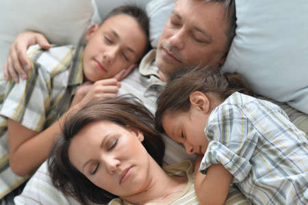 Portrait of sleeping brother, sister and father in roomの写真素材