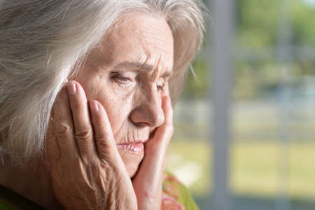 Portrait of sad senior woman with headacheの写真素材