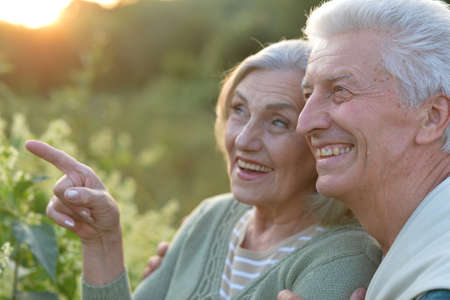 Senior couple posing in the park, man pointing with finger