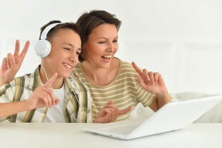 Mother and son using modern laptop at home