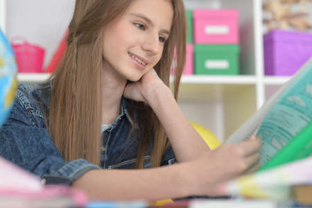 Cute girl doing home work at deskの写真素材