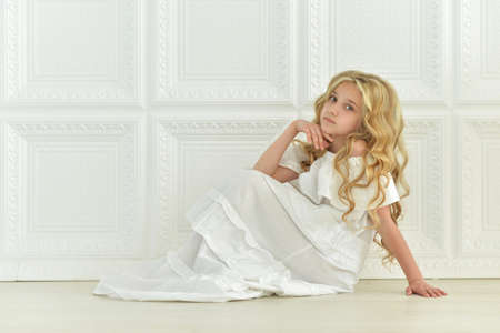 Beautiful girl in white dress sitting on the floor in studioの写真素材