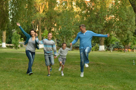 Happy young family running in summer parkの写真素材