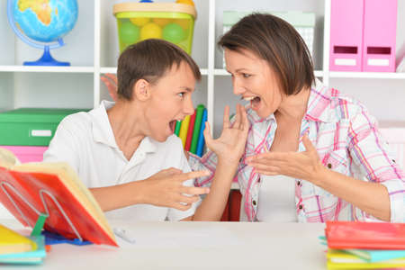 Emotional mother with her son doing homework at home