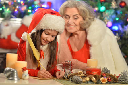 Smiling little girl with grandmother preparing for Christmasの写真素材