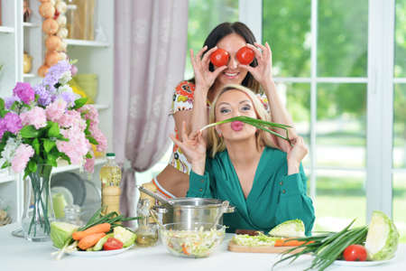 Two beautiful young women cooking together in kitchenの写真素材