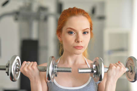 Sporty young woman training with dumbbells in gymの写真素材