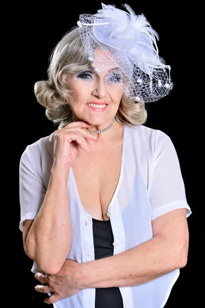 Beautiful senior woman in hat posing in the studio