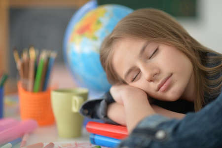 Cute schoolgirl sleeping at her homework at homeの写真素材