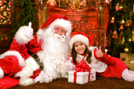 Santa Claus in a traditional costume with a girlの写真素材