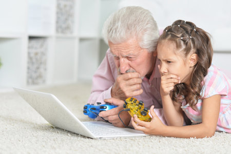 Emotional grandfather and granddaughter playing computer game