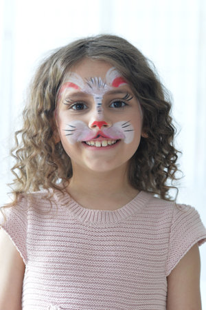 Cute girl with face painted as rabbit posing