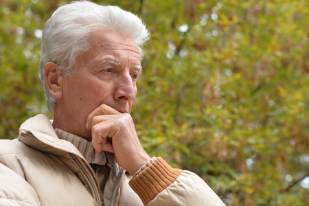 Serious old man looking in park on green backgroundの写真素材