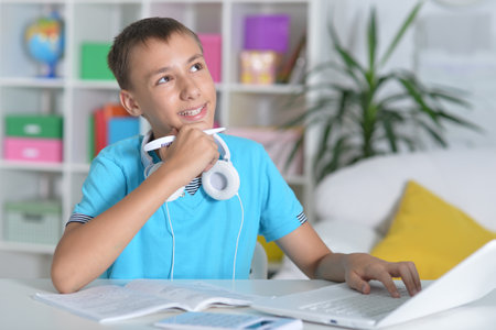 boy does homework with a laptop at a desk