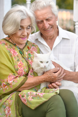 elderly couple holds a cat in their arms in the summerの写真素材