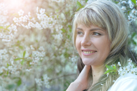 portrait of a beautiful young woman posing by cherry treeの写真素材
