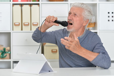 Senior old nice man singing into microphoneの写真素材