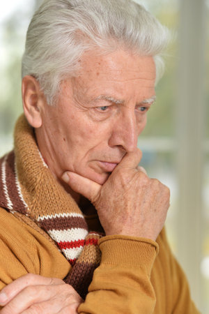 Aged man smiling at camera, chin on handsの写真素材