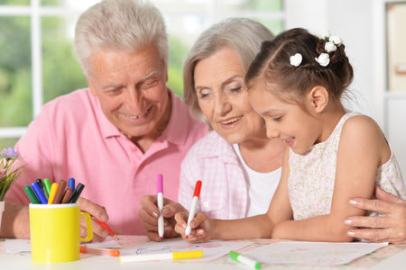girl with grandparents drawing at the table
