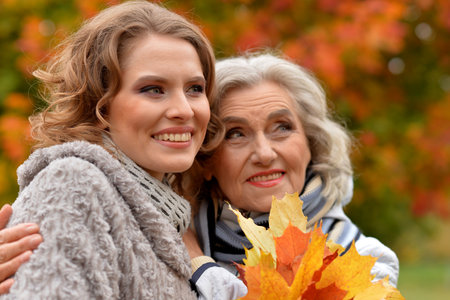 Portrait of an elderly woman with her daughter in autumn.