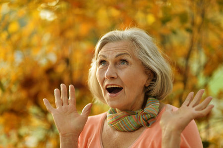 Senior woman walking in the park in autumn.